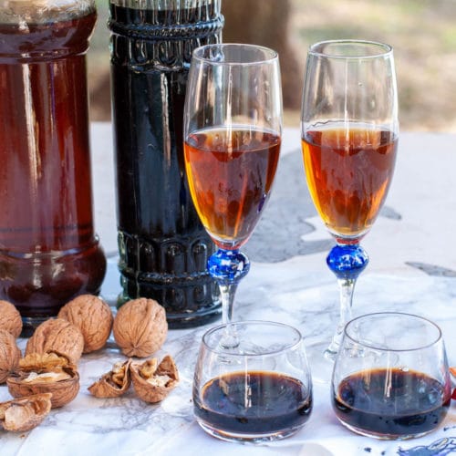 Green walnut liqueur Nocino poured in glasses