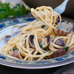 linguine alle vongole served in a plate and a fork getting a bite