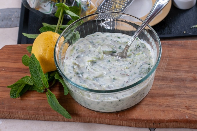 yoghurt sauce on a serving bowl herbs and lemon on the side