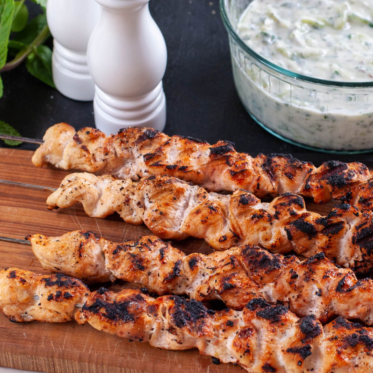 bbq chicken breast on skewers with the yogurt sauce in the back