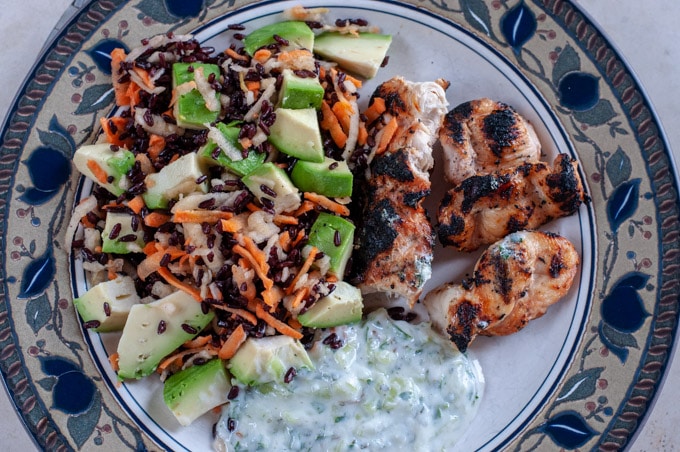 bbq chicken skewers with yogurt sauce and black rice salad served on a plate