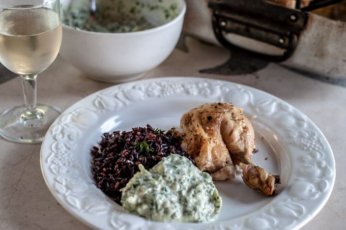 Roasted chicken dinner with black rice and yogurt sauce on a plate