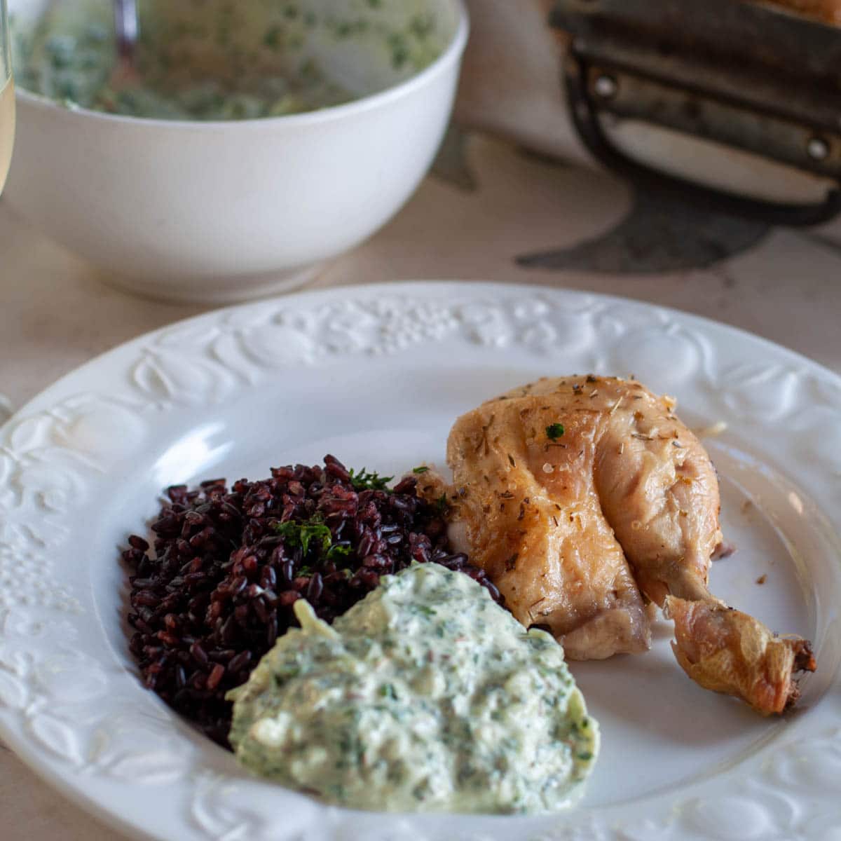 Low fat roasted chicken dinner on a plate with black rice and yogurt sauce