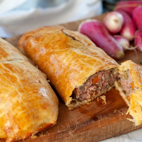 Beef sausage hand pies on a cutting board one pie cut open