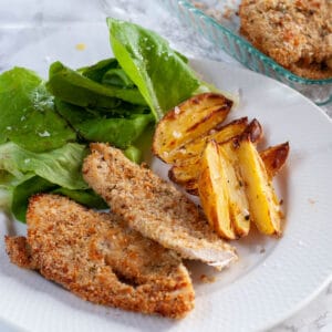 Braked breaded chicken breast served on a plate with salad and potatoes