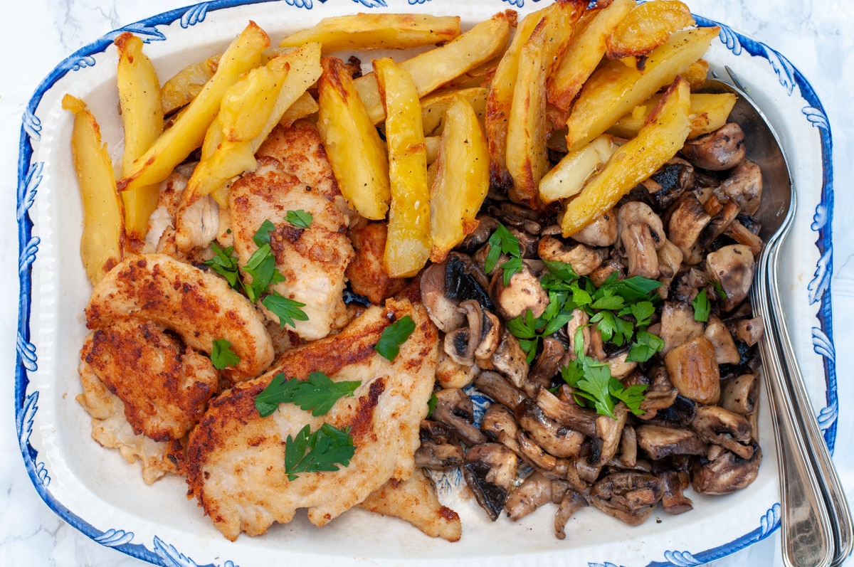 chicken Marsala served with mushrooms and potatoes on a serving dish 