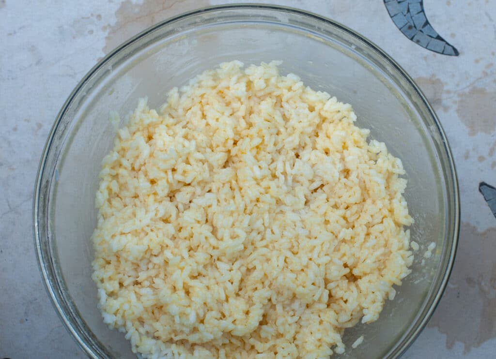 Boiled rice in a bowl mixed with butter and parmesan