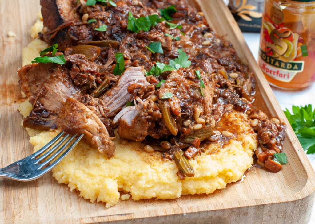 wild boar stew with chocolate over polenta and a fork lifting a piece of meat