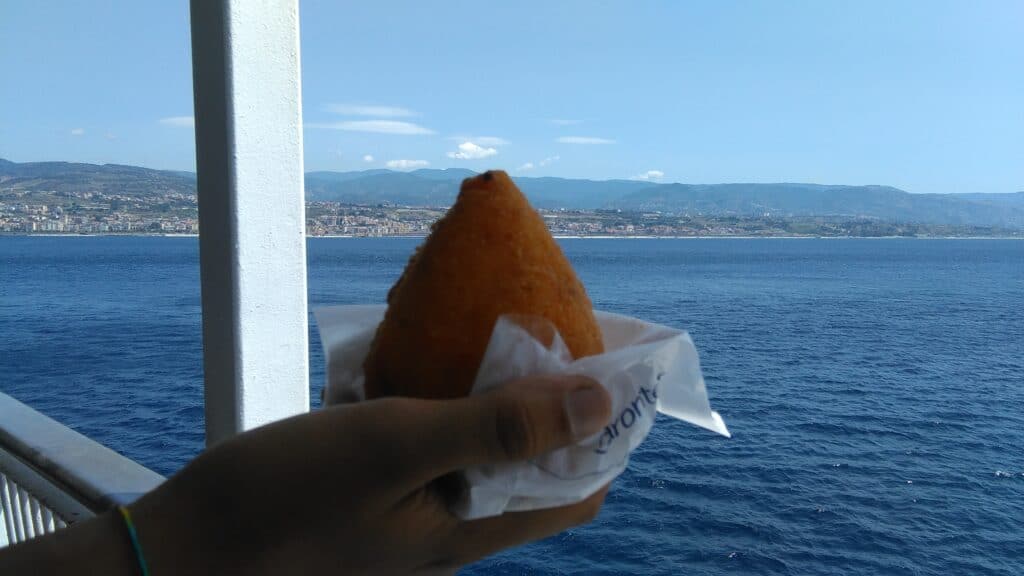 arancino hold with Sicily in the bachground