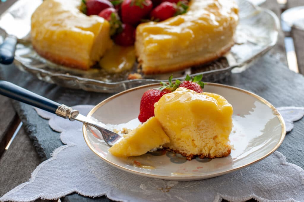 lemon magic cake filled with strawberries on a dish fork getting a bite