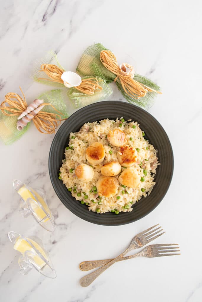 Pan-seared scallops served on top of a risotto with bacon and peas