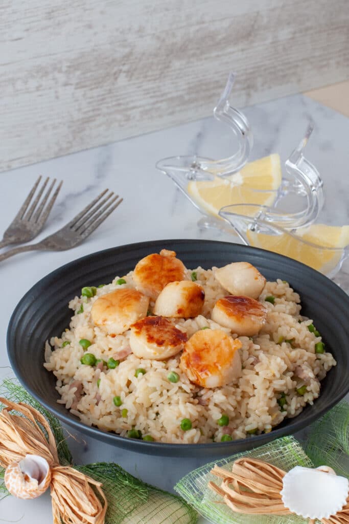 Pan-seared scallops served on top of a risotto with bacon and peas