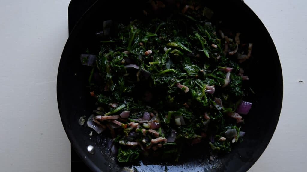 spinach cooking with bacon and onion