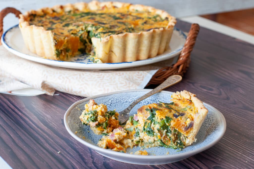 Italian Spinach Ricotta Pie With Caramelized Squash slice served on a plate and a fork getting a bite