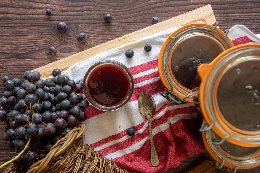 open jar of jam with grapes next to it