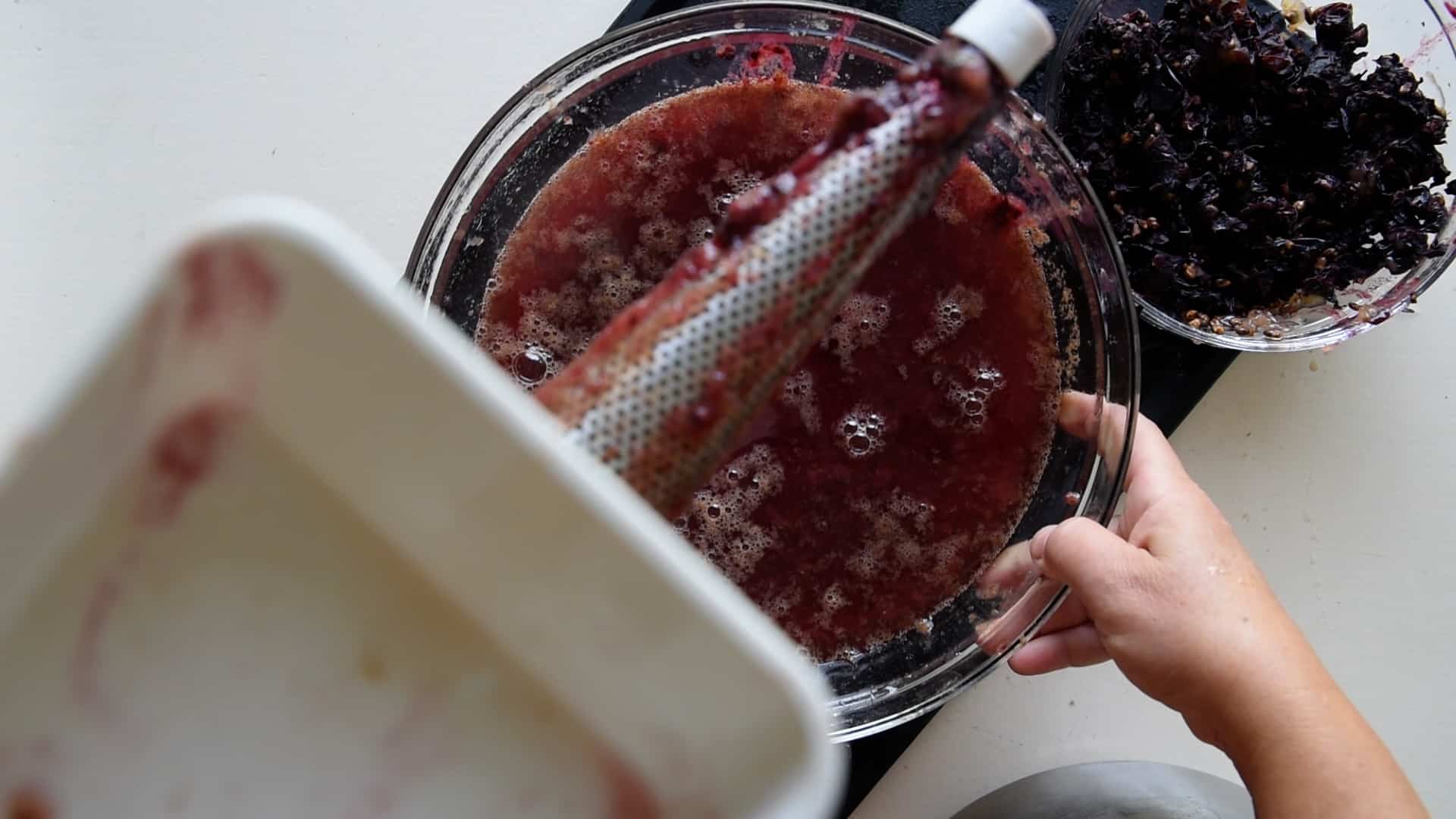 mess passing grape through a a fruit strainer