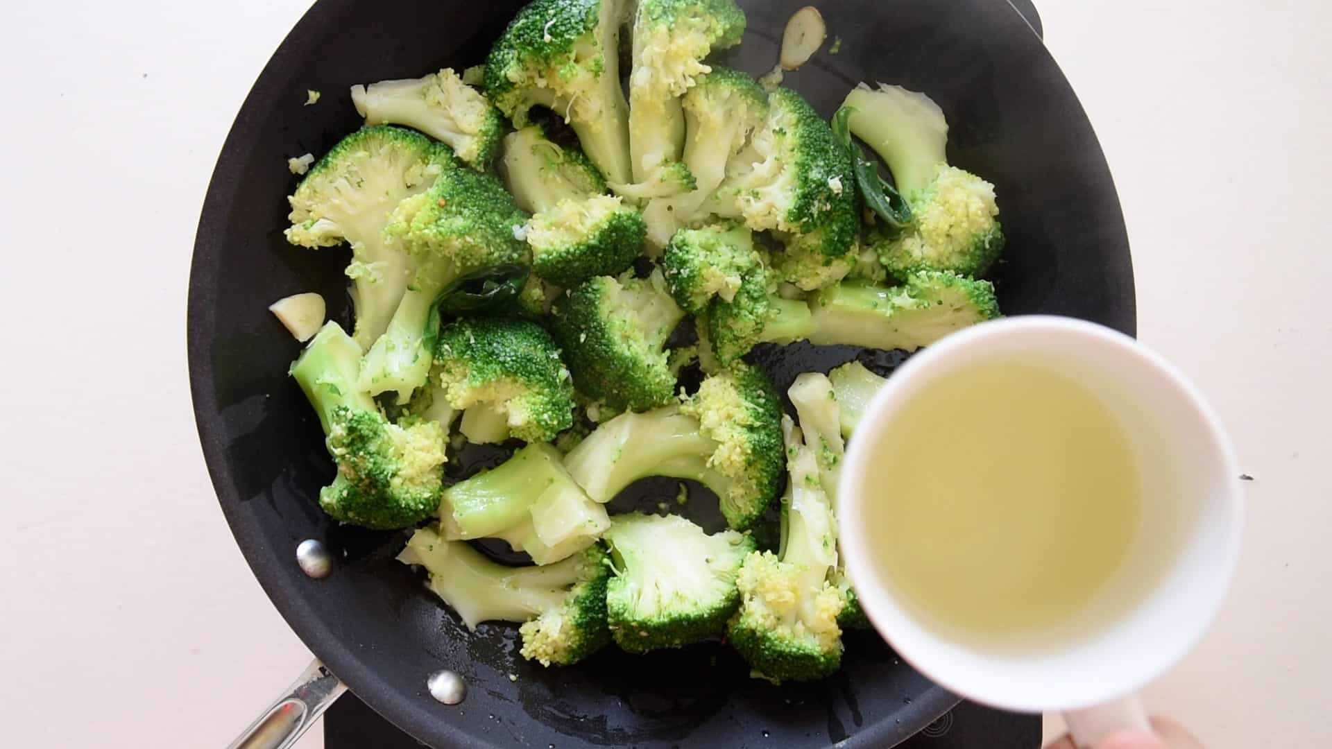 Add some cooking water to the sauteed broccoli