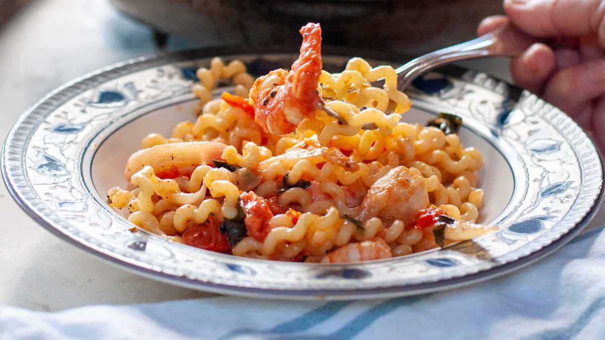 shrimp tomato pasta with a fork holding a bite