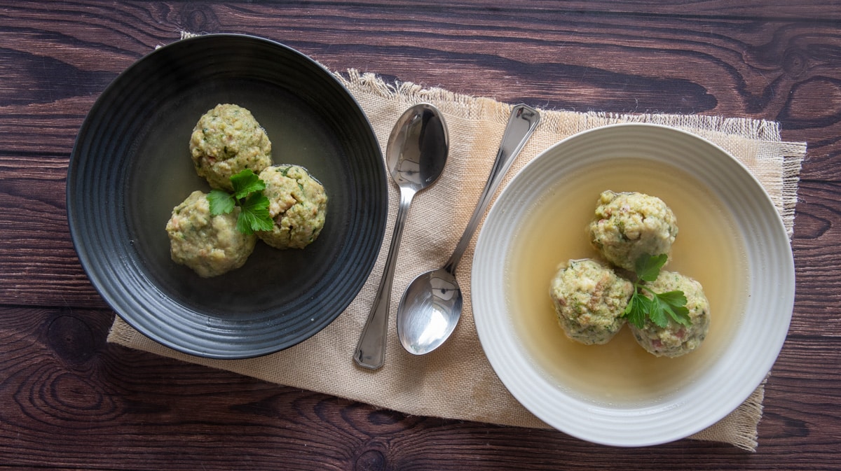 Canederli Italian Bread Dumplings served with broth in back and white plates
