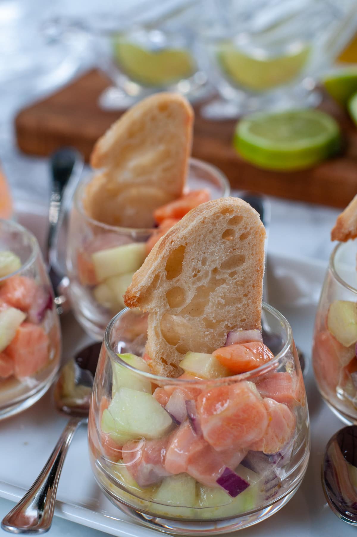 Salmon tartare served in a small glass with a slice of baguette