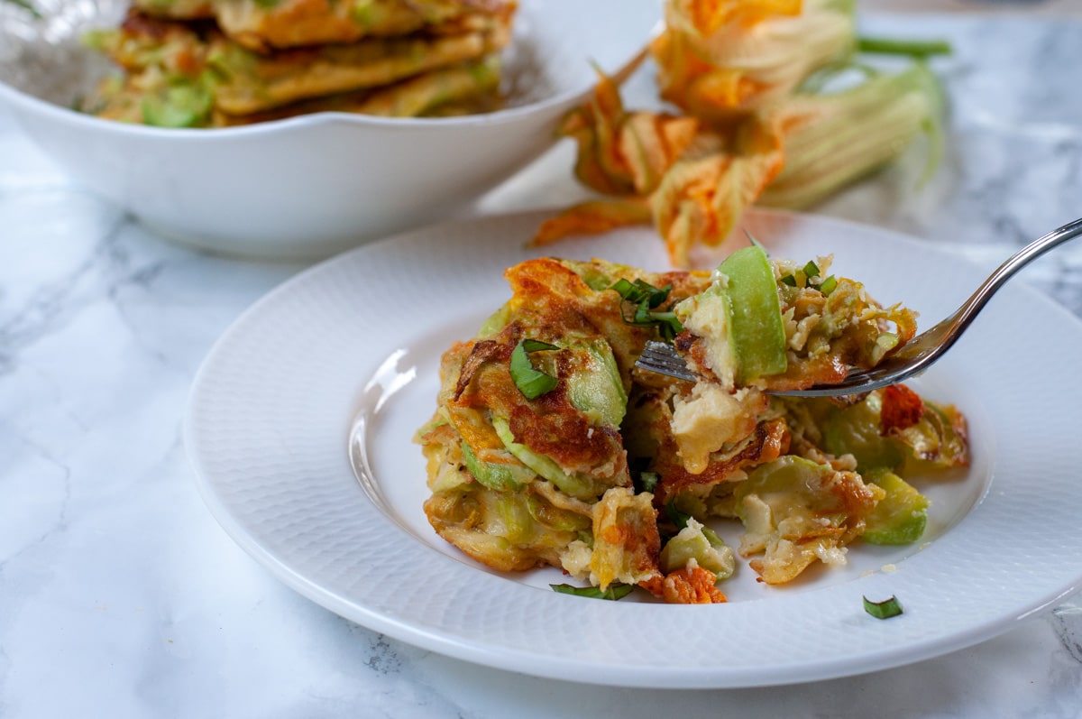 italian zucchini fritters served on a plate and a fork picking up a bite