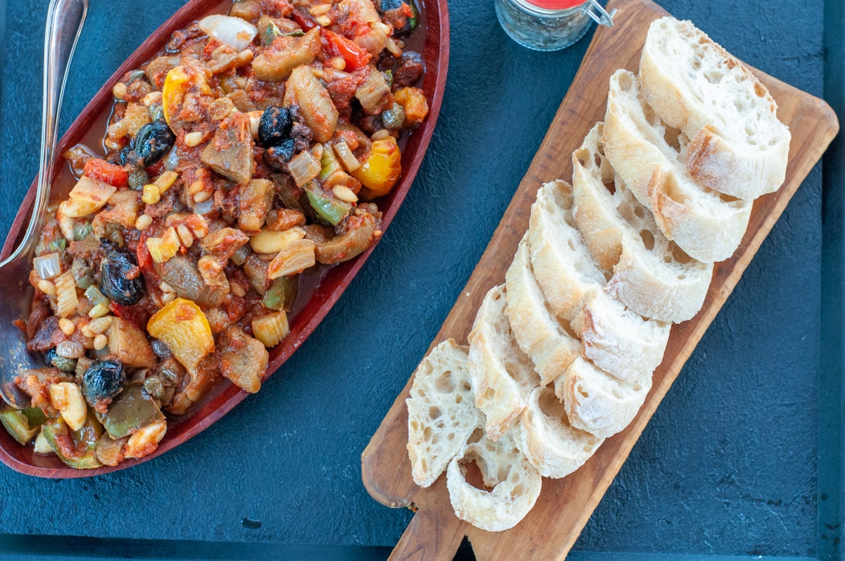 Caponata on a serving dish and slices of baguette