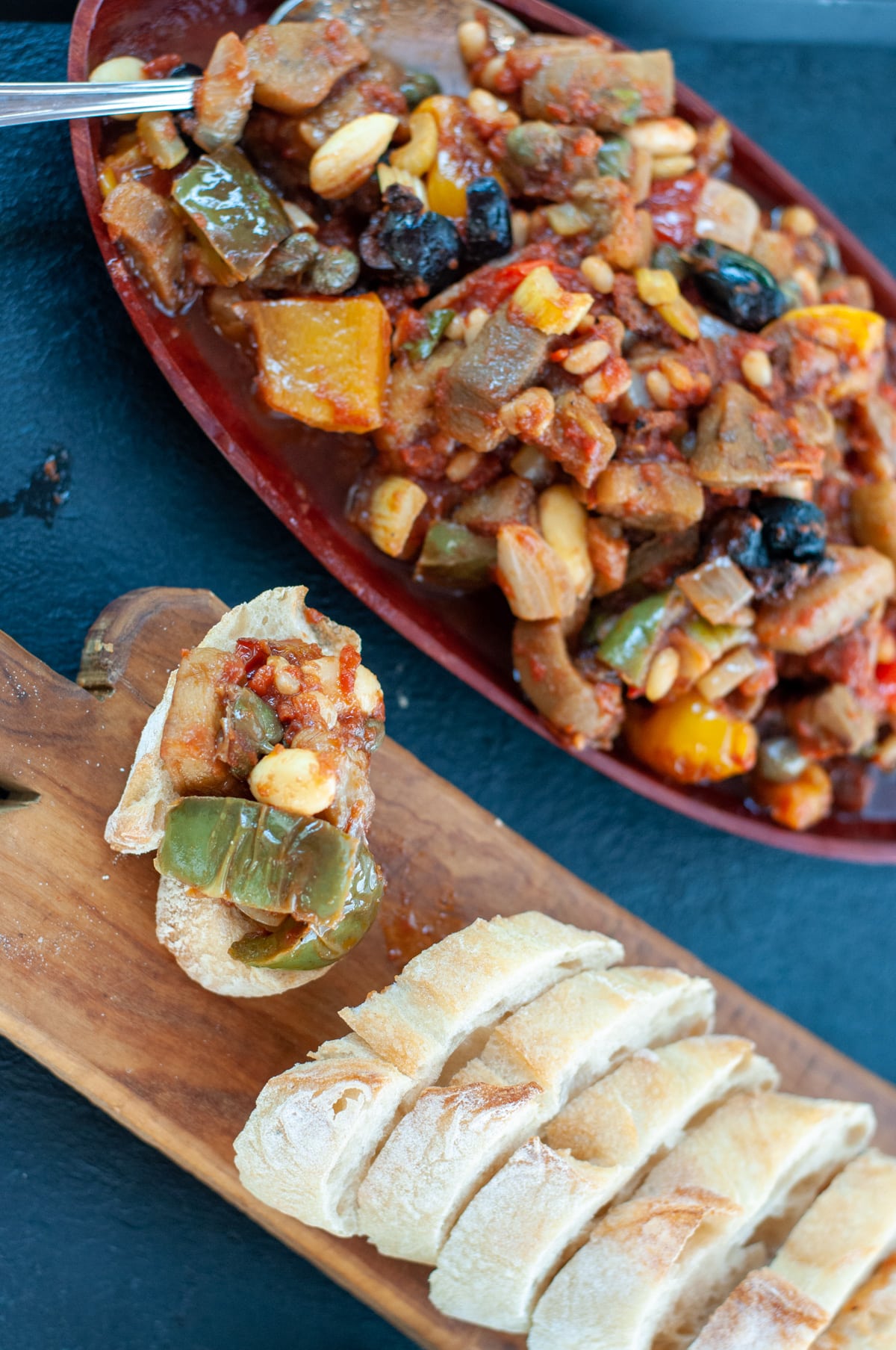 Vegetable caponata on a try and on a piece of crusty bread