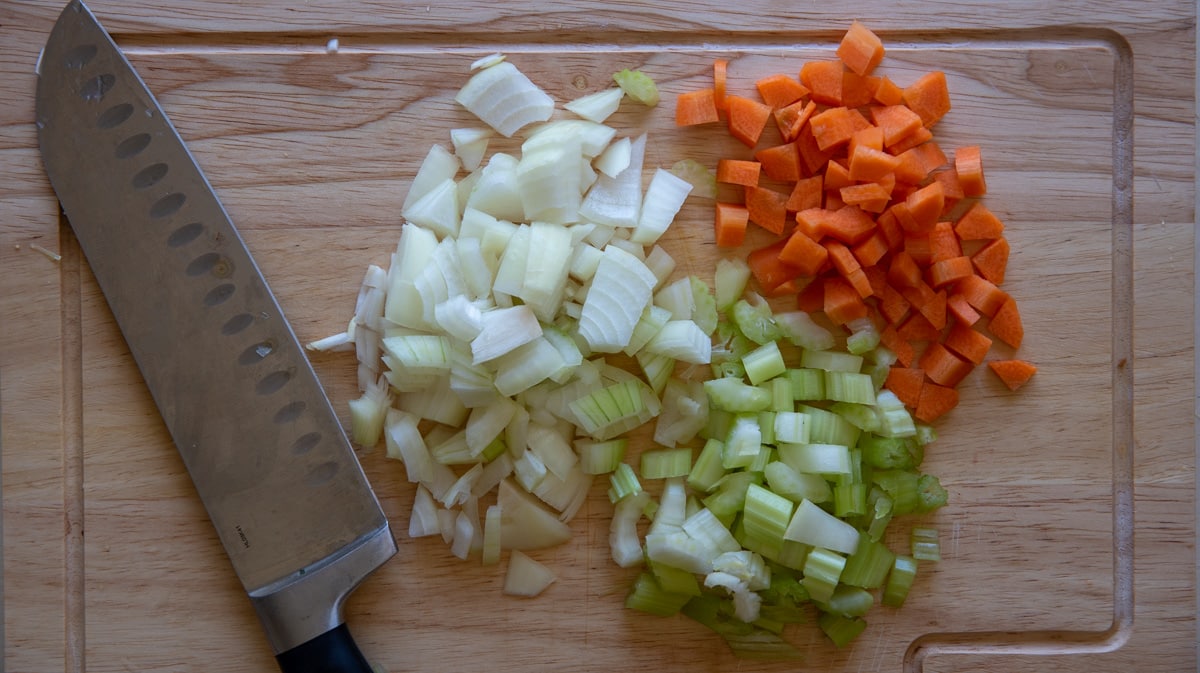 onion, carrot and celery chopped on a chopping board