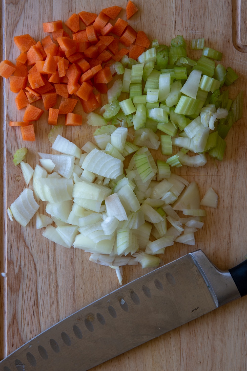 onion, carrot and celery chopped on a chopping board