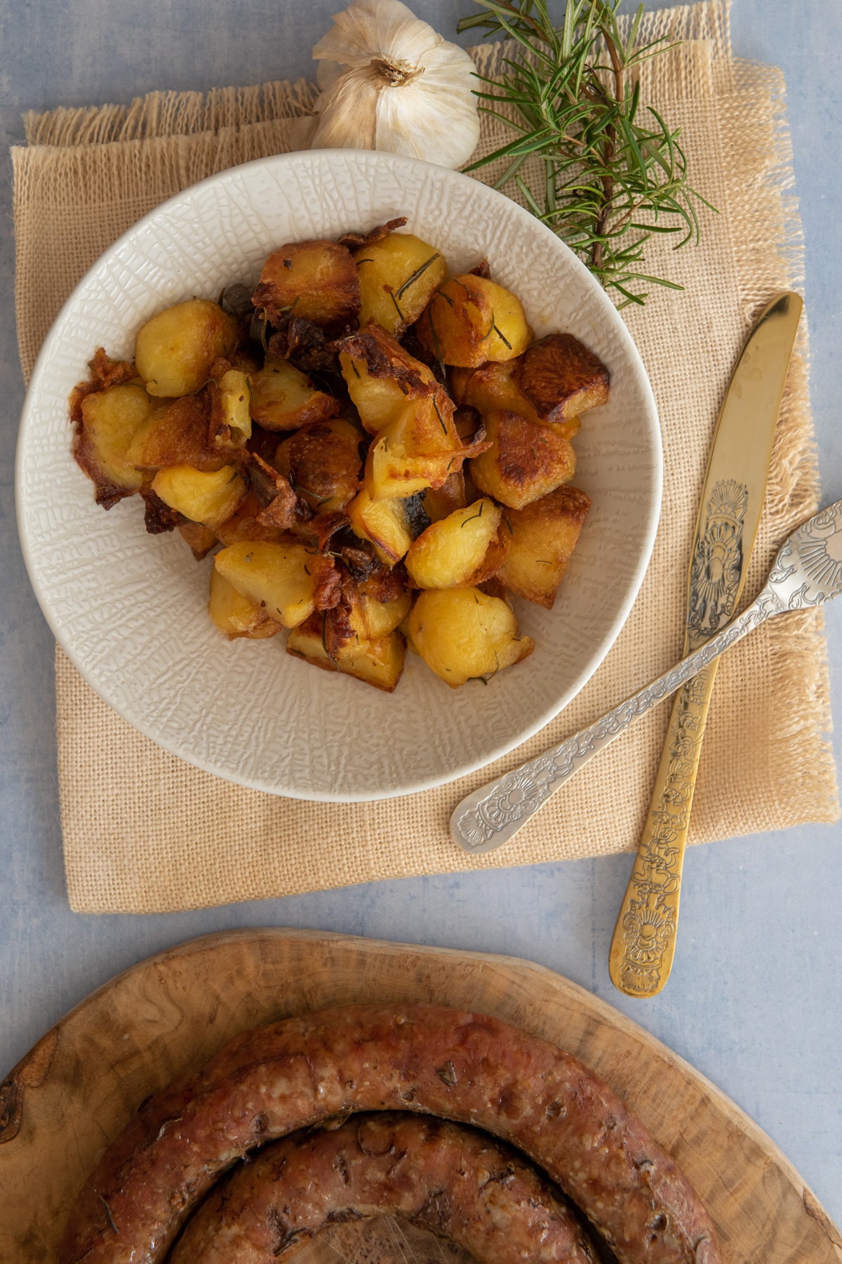 Easy Crispy Italian Roasted Potatoes Recipe with rosamary and garlic served with Italian sausage