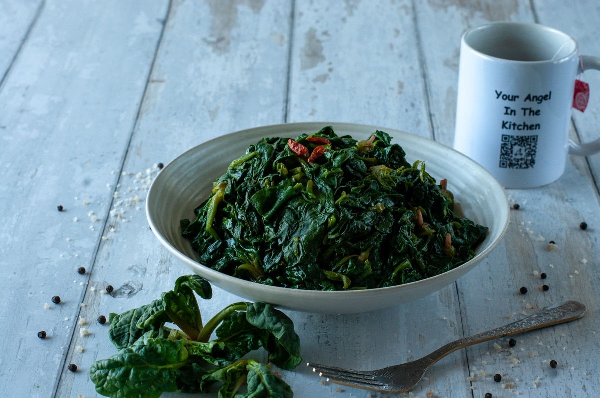 sauteed spinach on a plate beside a mug with our QRcode