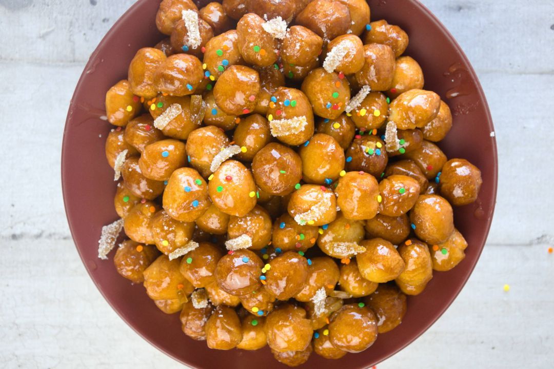 Struffoli covered with colored sugar and caramellized orange peels