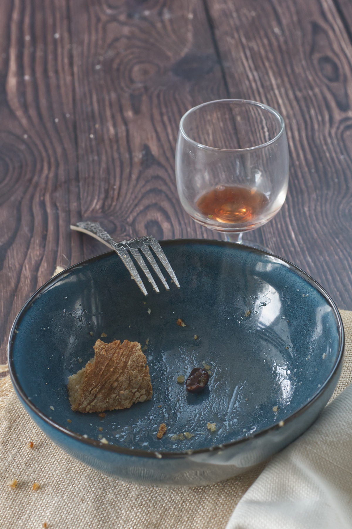 and empty plate with a piece of bread and an empty glass of red wine
